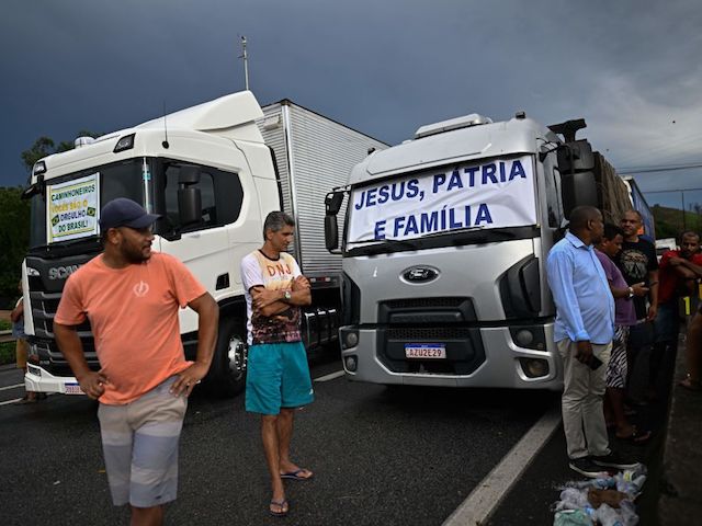 Supporters of President Jair Bolsonaro stand in front of trucks with messages related to his campaign slogan, during a blockade on the Via Dutra BR-116 highway between Rio de Janeiro and Sao Paulo, in Barra Mansa in the Brazilian state of Rio de Janeiro, on October 31, 2022, as an apparent protest, mainly by truck drivers, the far-right president's defeat in the presidential run-off election. - Truckers and other protesters on Monday blocked some highways in Brazil in an apparent protest over the electoral defeat of Bolsonaro to leftist Luiz Inacio Lula da Silva, authorities said. (Photo by Mauro PIMENTEL / AFP) (Photo by MAURO PIMENTEL/AFP via Getty Images)