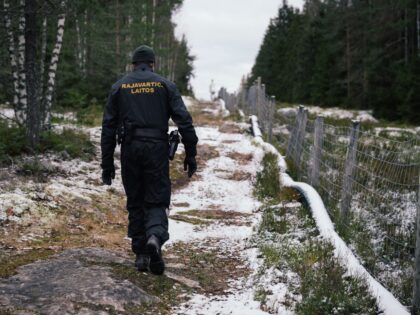Senior border guard officer Juho Pellinen walks along a fence marking the boundary area be