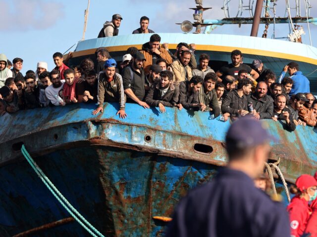Rescued refugees and migrants stand aboard a boat at the town of Paleochora, southwestern