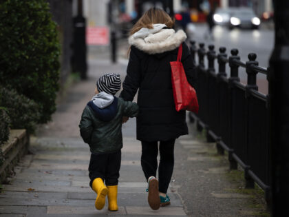 LONDON, ENGLAND - JANUARY 04: A child and parent walk near a closed primary school in Deptford on January 04, 2021 in London, England. Primary schools across London and southeast England will remain closed to most pupils until January 18th, and secondary schools in England will stagger their return in …