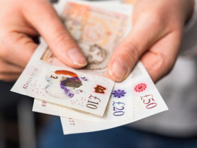 Close-up of a woman holding modern polymer ten, twenty and fifty pound notes.