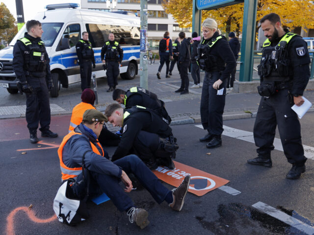BERLIN, GERMANY - OCTOBER 20: Police use a solvent to unstick activists from the climate a