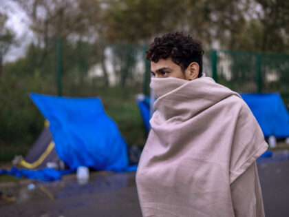 CALAIS, FRANCE - NOVEMBER 04: A teenage migrant uses a blanket to try and keep warm at a camp in an industrial zone on November 04, 2022 in Calais, France. Around 2,000 migrants are reportedly living in northern France, many sleeping rough scattered around the Calais and Dunkirk area, as …