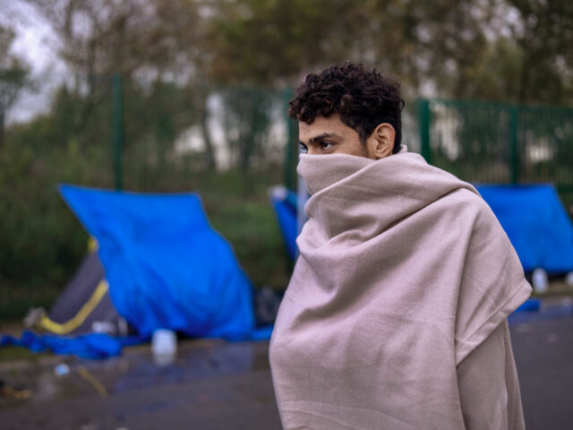 CALAIS, FRANCE - NOVEMBER 04: A teenage migrant uses a blanket to try and keep warm at a c