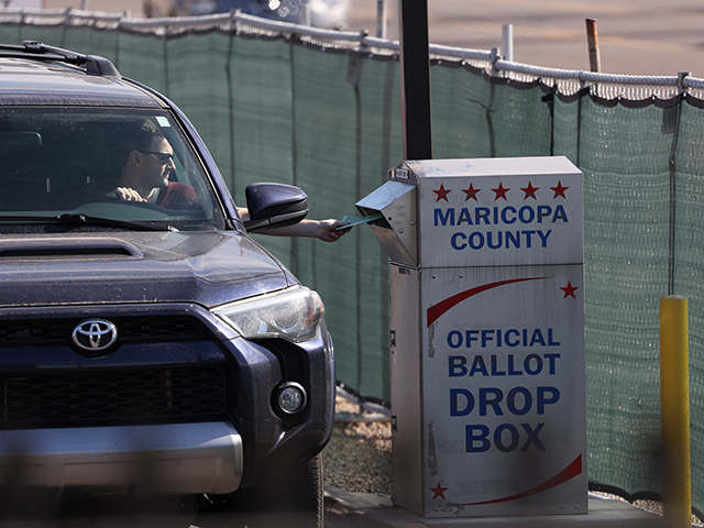 A voter drops his ballot into a drop box at the Maricopa County Tabulation and Election Ce