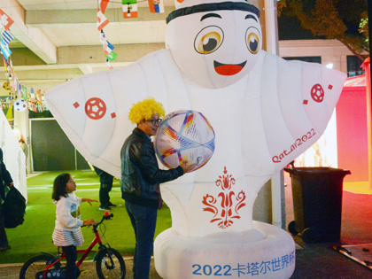 A man poses for a photo in front of an inflatable "La'eeb", which is the Qatar 2022 mascot, on the street on November 20, 2022 in Shanghai, China. The FIFA World Cup Qatar 2022 kicks off on November 20. (Photo by VCG/VCG via Getty Images)