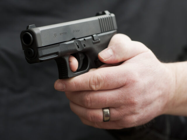 "A man holding a modern polymer pistol (Glock 30SF, .45 caliber) with his finger on t