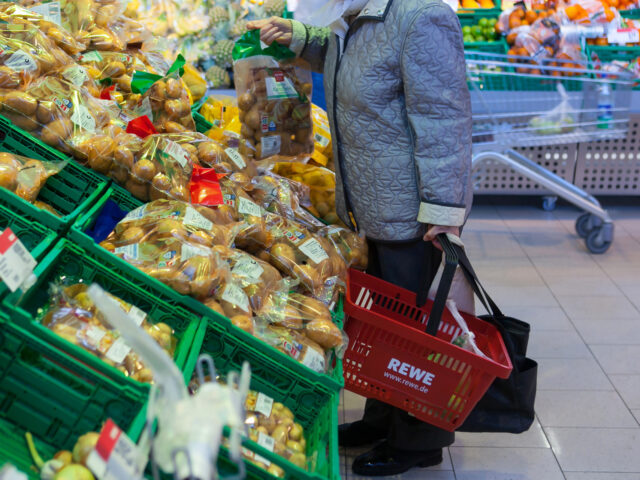 A customer holds a bag of potatoes in the vegetable aisle in a Rewe supermarket, operated