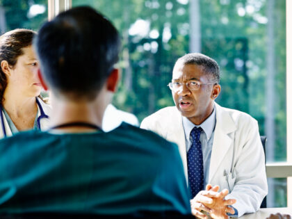 Mature male doctor leading discussion in medical team meeting in conference room in hospit