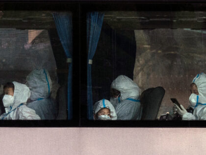 Residents, including children, wear protective clothing and masks as they wait on a bus outside a residential compound before leaving, as part of epidemic control to prevent the spread of COVID-19, on November 15, 2022 in Beijing, China. Though the government recently revised its COVID strategy, it has said it …