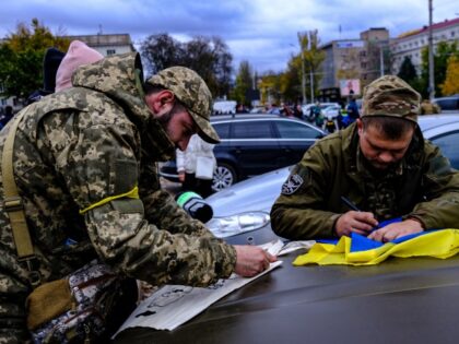 KHERSON, UKRAINE - NOVEMBER 19: Ukrainian soldiers signs the Ukrainian flags and a cloth bag at Svobody Square (Freedom Square) as people gather to celebrate the liberation following Russia's withdrawal from Kherson in Ukraine on November 19, 2022. (Abdullah Unver/Anadolu Agency via Getty Images)