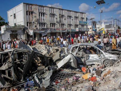 People walk amidst destruction at the scene, a day after a double car bomb attack at a busy junction in Mogadishu, Somalia Sunday, Oct. 30, 2022. Somalia's president says multiple people were killed in Saturday's attacks and the toll could rise in the country's deadliest attack since a truck bombing …