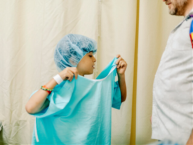 Kid finding out how to dress up the hospital gown - stock photo