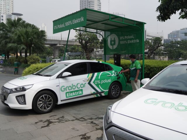 A Grab Holdings Inc. GrabCar driver plugs an electric vehicle "Elektrik" into a charging s