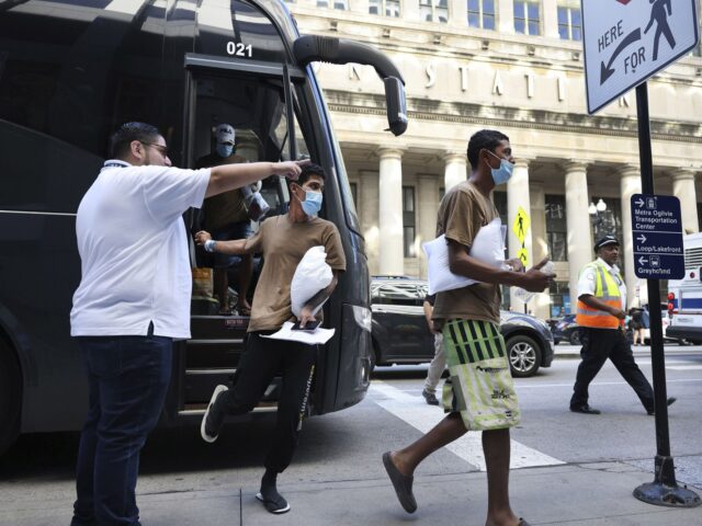 Migrants are led from one bus to another after arriving from Texas at Union Station on Sep