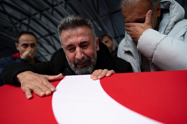 Nurettin Ucar (C) grieves over a flag-draped coffin at the funeral of his daughter Yagmur