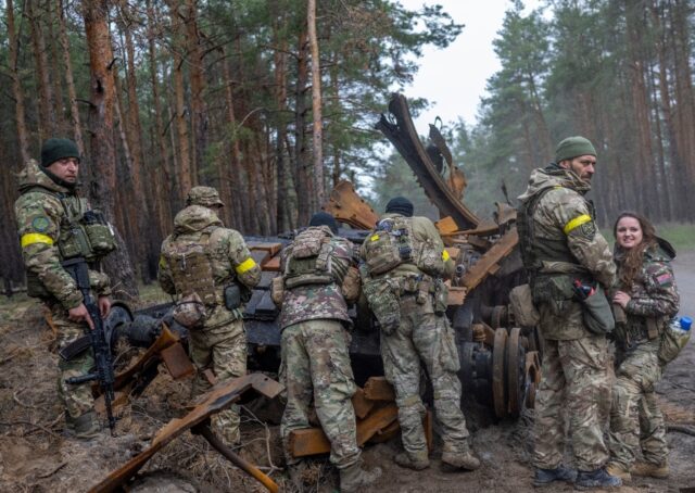 Ukrainian soldiers and volunteer fighters inspect a destroyed Russian tank in eastern Ukra