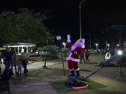 A man wearing a Santa Claus costume gestures to a camera as he is being filmed for a Christmas commercial in Maracaibo, Venezuela, Thursday, Oct.13, 2022. (AP Photo/Ariana Cubillos)
