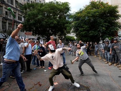 Protesters throw bottles glasses at the Lebanese Central Bank building, background, where