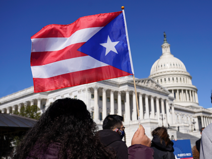 A woman waves the flag of Puerto Rico during a news conference on Puerto Rican statehood on Capitol Hill in Washington, March 2, 2021. The U.S. House has passed a bill that would allow Puerto Rico to hold the first-ever binding referendum on whether to become a state or gain …