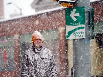 A man is covered in snow on Fenn Street in Pittsfield, Mass, Friday, Dec. 16, 2022. (Ben Garver/The Berkshire Eagle via AP)