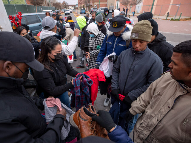 Migrants look through donated clothing on a street in downtown El Paso, Texas, Sunday, Dec