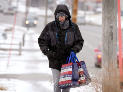 Greg Behrens, of Des Moines, Iowa, tries to stay warm as he makes his way on a snow covered sidewalk, Wednesday, Dec. 21, 2022, in Des Moines, Iowa. (AP Photo/Charlie Neibergall)