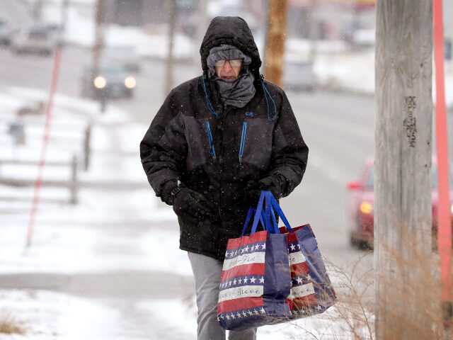 Greg Behrens, of Des Moines, Iowa, tries to stay warm as he makes his way on a snow covere