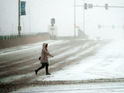 A pedestrian walks a cross the street in Rosemont, Thursday, Dec. 22, 2022. Frigid air is moving through the central United States to the east, with windchill advisories affecting about 135 million people over the coming days, weather service meteorologist Ashton Robinson Cook said Thursday. (AP Photo/Nam Y. Huh)