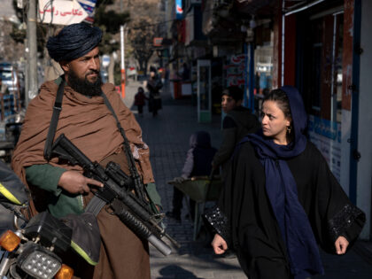 A Taliban fighter stands guard as a woman walks past in Kabul, Afghanistan, Monday, Dec. 26, 2022. Recent Taliban rulings on Afghan women include bans on university education and working for NGOs, sparking protests in major cities. Security in the capital Kabul has intensified in recent days, with more checkpoints, …