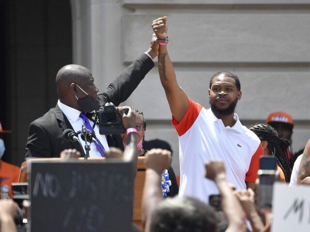 FILE - Attorney Benjamin Crump, left, holds up the hand of Kenneth Walker during a rally on the steps of the Kentucky State Capitol in Frankfort, Ky., on June 25, 2020. Walker, the boyfriend of Breonna Taylor who fired a shot at police as they burst through Taylor's door the …