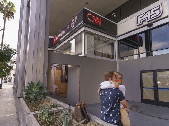 A couple hugs outside the lobby of the CNN tower with boarded-up windows in the Hollywood section of Los Angeles on Sunday, Nov. 1, 2020. A report by the Armed Conflict Location & Event Data Project listed California as a "moderate risk" for election-related violence following Election Day, regardless of …