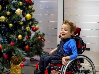 Child in wheelchair enjoys Christmas tree