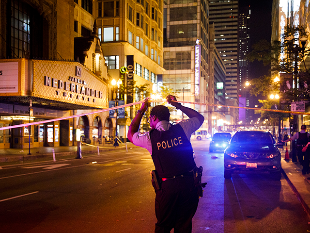 An officer walks under police tape near the intersection of West Randolph and North State