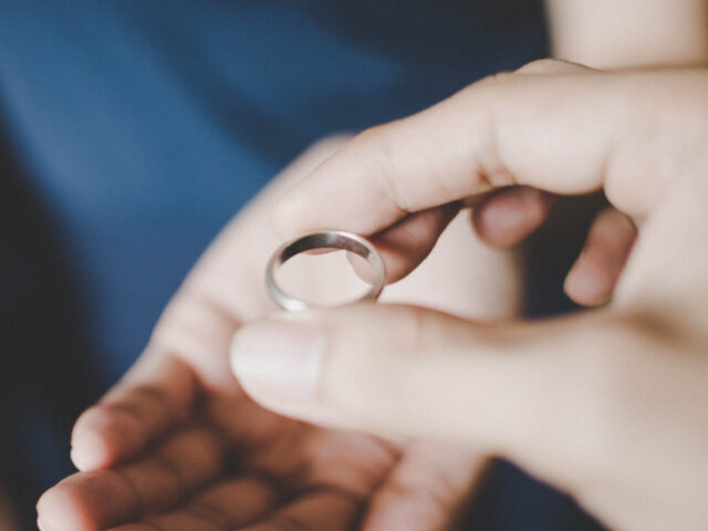 A young couple's hands holding a wedding ring, a concept of divorce - stock photo