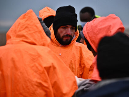 Migrants, picked up at sea by an Royal National Lifeboat Institution (RNLI) lifeboat whilst attempting to cross the English Channel, wait on the shore before being escorted by Immigration Officers, at Dungeness on the southeast coast of England, on December 9, 2022. (Photo by Ben Stansall / AFP) (Photo by …
