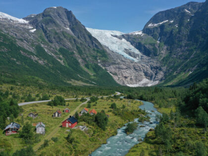 FJAERLAND, NORWAY - AUGUST 12: In this aerial view from a drone the Boyabreen glacier lies above rock it ground smooth and once covered deep in ice while meltwater rushes down a stream past cabins on August 12, 2020 near Fjaerland, Norway. The Boyabreen glacier is an arm of the …