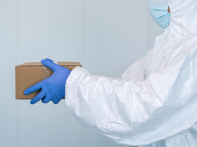 A male nurse in a protective suit PPE shows a box in the hospital. Coronavirus. The healthcare worker receives medical supplies to care for patients with coronavirus or covid 19. Doctor wearing a PPE.