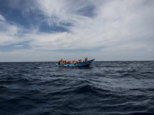 AT SEA - MARCH 27: A migrant leaves a wooden boat to board a RHIB (rigid-hulled inflatable
