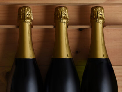 Closeup of three Champagne bottles in a wood case.