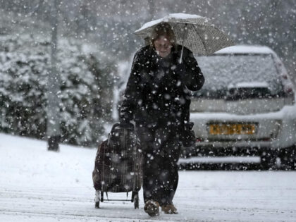 NORTHWICH, UNITED KINGDOM- DECEMBER 10: A woman makes her way through a snow flurry, the first significant snow fall in Cheshire this Winter on December 10, 2022 in Northwich, United Kingdom. The UK Health Security Agency (UKHSA) issued a cold-weather alert that will run until Monday morning, as many across …