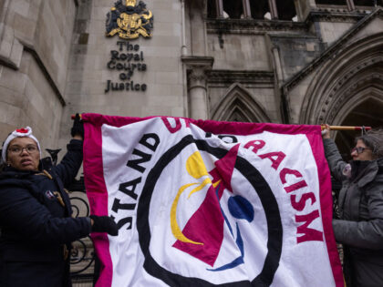 LONDON, ENGLAND - DECEMBER 19: 'Stand up to Racism' campaigners dismantle a flag after staging an anti-Rwanda deportations demo outside the Royal Courts of Justice on December 19, 2022 in London, England. London's High Court has ruled that the government's Rwanda deportation scheme is lawful after the initial flight was …