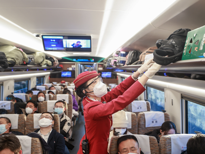 A stewardess arranges suitcases on a high-speed train from Beijing to Nanchang on December