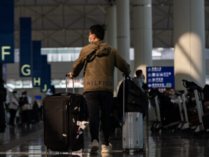 HONG KONG, CHINA - DECEMBER 30: Travellers walk with their luggage at the departure hall of the Hong Kong International Airport on December 30, 2022 in Hong Kong, China. Authorities around the world are imposing or considering curbs on travellers from China as COVID-19 case there surge following its relaxation …