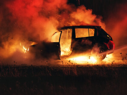 Firefighters extinguish a car fire on Nova Scotia's highway 102. Shot at high iso with light grain.