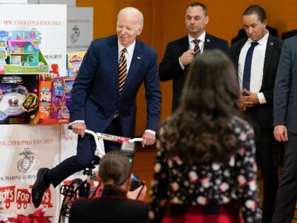 President Joe Biden pretends to ride a bike during a Toys for Tots sorting event at Joint Base Myer-Henderson Hall in Arlington, Va., Monday, Dec. 12, 2022. (AP Photo/Patrick Semansky)