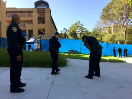 Univeristy of California Irvine campus police stand outside the gated Student Center, as m