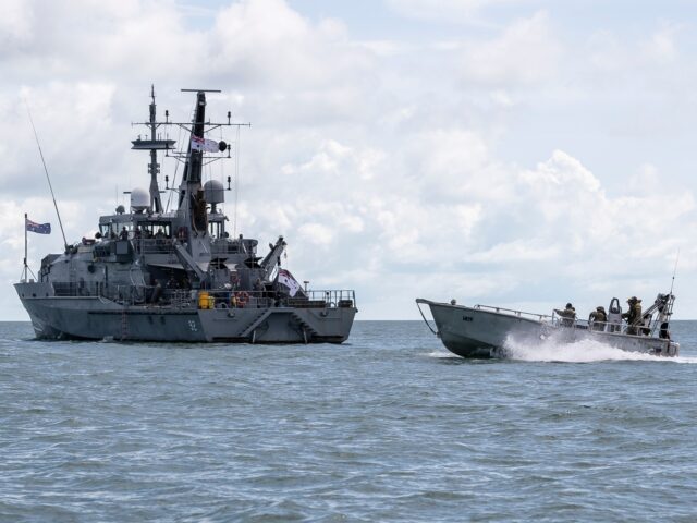 SAIBAI ISLAND, AUSTRALIA - MARCH 26: The HMAS Wollongong is passed by a boat with Australi