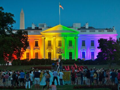 People gather in Washington's Lafayette Park to see the White House illuminated with