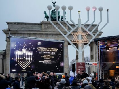 People attend the official lighting of a giant Hanukkah Menorah, set up by the Jewish Chabad Educational Center ahead of the Jewish Hanukkah holiday, in front of the Brandenburg Gate at the Pariser Platz in central Berlin, Germany, Sunday, Dec. 18, 2022. Holocaust survivors from around the world are marking …